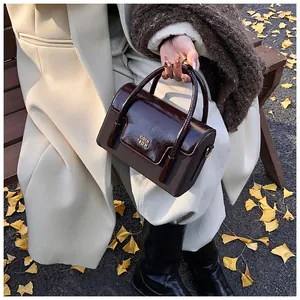 Detail of vintage reddish-brown square handbag with glossy patent leather and gold logo