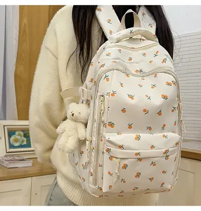 Detail of cream backpack with orange fruit print featuring a plush bear charm accessory