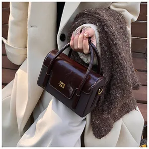 Detail of dark brown glossy patent leather handbag with gold COIK 2DN logo hardware