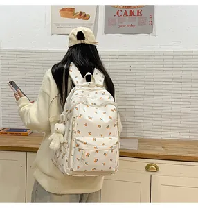 Detail of cream backpack with orange fruit prints and a cute white teddy bear charm