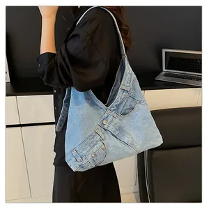 Detail of light blue washed denim shoulder bag with functional pockets and metal button