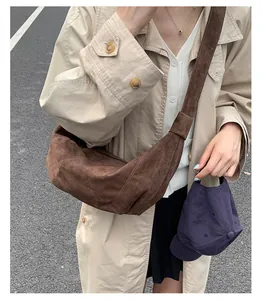 Close-up of a dark brown suede crescent bag worn with a beige trench coat on the street