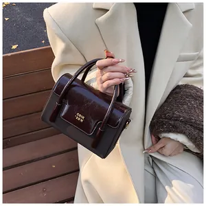 Detail of a vintage contrast handbag with gold logo and textured coffee brown leather