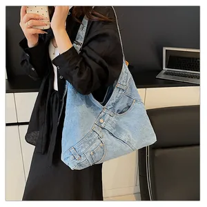 Detail of light blue denim tote bag with jeans pocket design and metal buttons