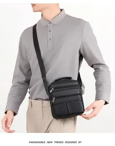 Sac bandoulière vertical en cuir noir à texture litchi porté par un mannequin homme