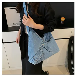 Detail of light blue denim shoulder bag featuring classic jeans pockets and metal buttons
