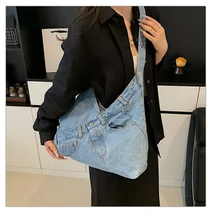 Detail of light blue denim crossbody bag featuring jeans waist design and metal buttons