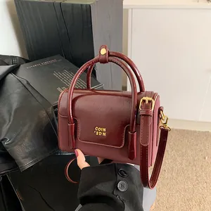Fashionable dark red crossbody bag with glossy finish and gold hardware details