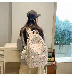 Close-up of white cherry print backpack featuring a cute white plush bear pendant
