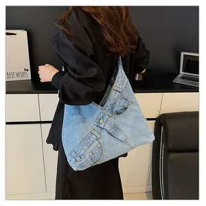 Detail of light blue washed denim tote bag showing functional pockets and metal rivets