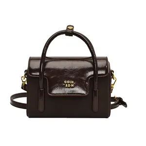 Premium dark brown glossy leather handbag with elegant gold lettering and shoulder strap