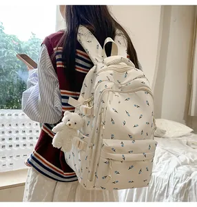 Detail view of white backpack with blue tulip patterns and a cute plush bear charm