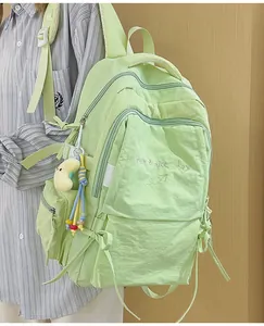 Dettaglio dello zaino in nylon verde chiaro con ricami e ciondolo a forma di luna