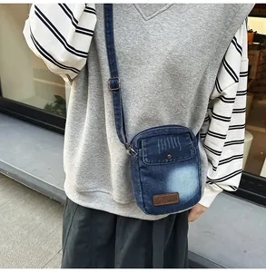 Detail of blue denim crossbody bag with brown leather patch and adjustable strap