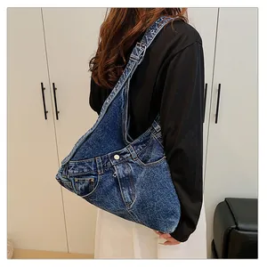 Detail of deconstructed denim shoulder bag with pocket features and adjustable strap