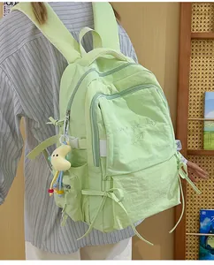 Vista laterale di uno zaino scolastico verde chiaro con fiocco e ciondolo a luna