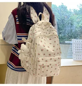 Detail of cream backpack with strawberry prints, heart patterns and plush bear charm