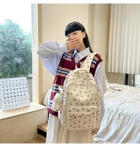 Detail of cream backpack with strawberry prints and a white plush bear charm