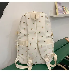 Detail view of the back of a beige floral backpack featuring adjustable padded straps