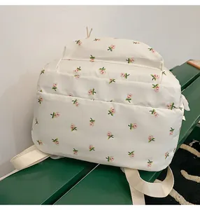 Detail of floral print backpack in ivory nylon fabric on a green display stand