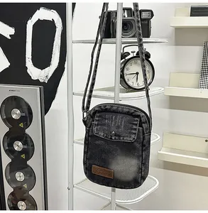 Close-up of black washed denim crossbody bag texture with vintage leather logo label