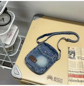 Detailed close-up of retro washed denim crossbody bag with brown leather logo patch