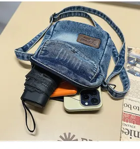 Detailed interior capacity of denim crossbody bag holding phone and folding umbrella