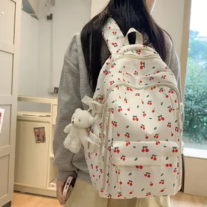 White backpack with red cherry print and plush bear charm for casual school wear