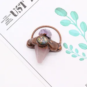 Détail macro du pendentif flèche avec améthyste, nacre d'ormeau et cristaux de quartz rose