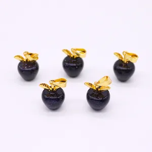 Detail van appelvormige blauwe goudsteen hangers met gouden bladaccenten op wit decor