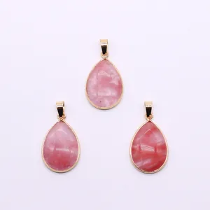 Detailed view of pink natural stone teardrop pendants with polished gold-plated metal frames