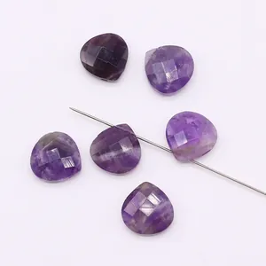 Close-up of six purple faceted heart-shaped stones with drill holes for DIY jewelry