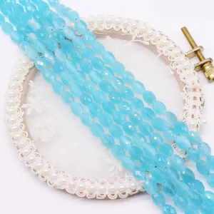 Detail of faceted oval light blue cat eye stone beads on elegant white lace background