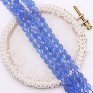 Detailed view of faceted oval blue cat eye stone beads on a white decorative lace tray