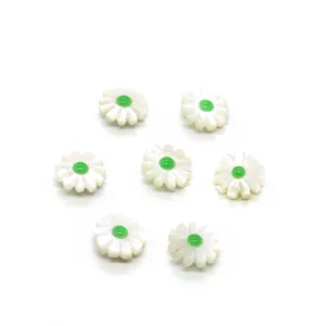 Detail of seven white shell daisy beads with green centers for DIY jewelry making