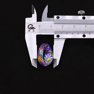 Detailed macro view showing a 16mm floral painted natural seashell bead with caliper scale