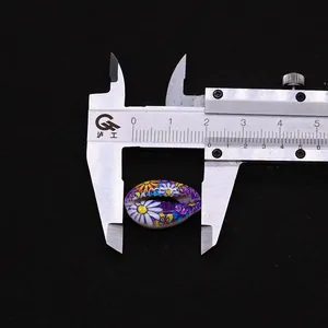 Detailed view of a 20mm floral painted natural seashell bead measured with a caliper