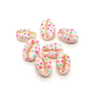 Detail view of seven white natural shells with pink green and blue star patterns for DIY