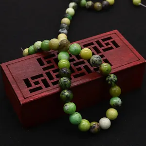 Polished natural green opal round beads for DIY jewelry making on a vintage red wooden box
