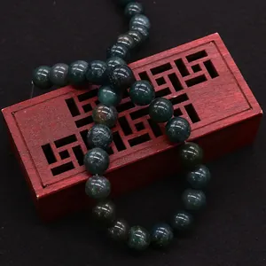 Polierte grüne Moosachat-Perlen auf einer roten Vintage-Holzbox für DIY-Schmuck