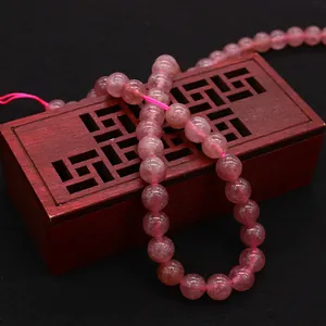 Pink strawberry quartz beads for DIY jewelry making on a vintage wooden box background