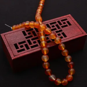 Natural red agate beads necklace displayed on a vintage carved wooden box centerpiece