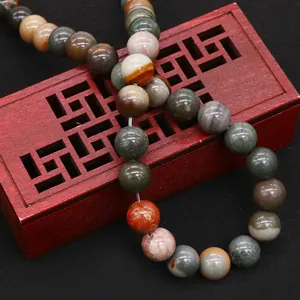 Natural picture jasper stone beads displayed on an ornate vintage wooden jewelry box