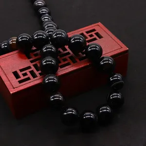 Polished natural black dragon vein agate beads displayed on a decorative red wooden box