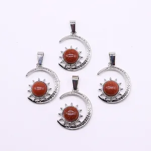 Macro shot of silver sun and crescent moon pendants with red sandstone inlay
