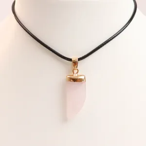 Macro detail of a chili-shaped rose quartz pendant with gold plating on a black cord