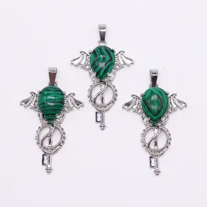 Close-up of angel wing silver key pendants with green malachite stone inlays