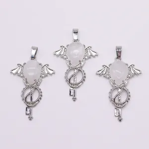 Macro detail of silver angel wing key pendants with white teardrop crystal stones