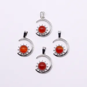 Detail of silver sun and moon pendants with round red gemstones on white background