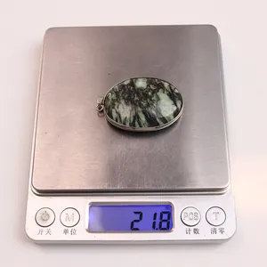 Macro detail of oval turquoise pendant on scale showing 21.8g weight with silver bezel
